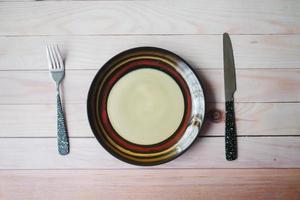 cutlery and empty plate on wooden background top down photo