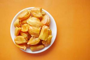 top view of slice of jackfruits in a bowl on orange background . photo