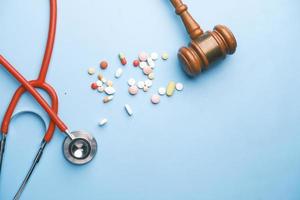 Top view of gavel, stethoscope and pills on blue background photo