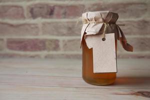 Miel fresca en un frasco de vidrio con una etiqueta vacía de papel. foto
