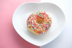 Donuts coloridos en placa con forma de corazón foto