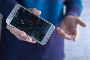 Close up of man hand holding broken smart phone. photo