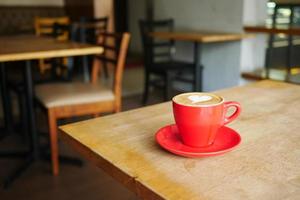 a cup of late coffee with flower shape design on top at cafe photo