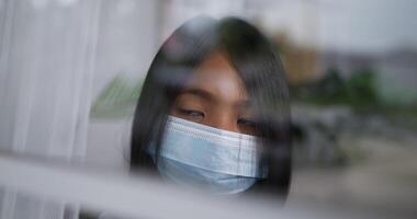 Closeup Teen girl wearing a surgical mask is looking out of the window. video