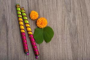 Festival indio dussehra y navratri, mostrando hojas doradas bauhinia racemosa y flores de caléndula con palos dandiya sobre un fondo de madera foto