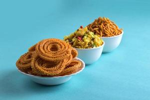 Indian Snack Chakli, chakali or Murukku and Besan Sev and chivada or chiwada on blue background. Diwali Food photo