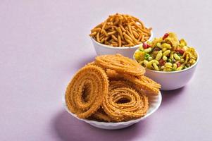 Indian Snack Chakli, chakali or Murukku and Besan Gram flour Sev and chivada or chiwada on pink background. Diwali Food photo