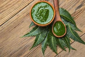 Medicinal Neem leaves with paste on wooden background photo