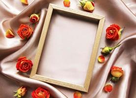 Flowers composition. Wooden frame and red  roses and leaves photo