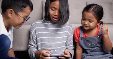 Happy little children enjoy playing mobile game on smartphone video