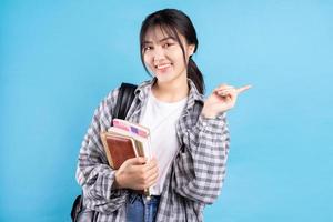 Asian female student with playful expression on blue background photo