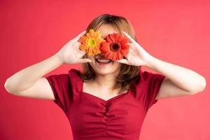 niña sosteniendo una flor roja y amarilla colocada sobre sus ojos