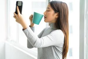 Mujer de negocios asiática de pie tomando selfie foto por ventana