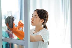 Beautiful Asian woman cleaning the bedroom glass door photo