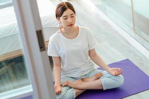 Hermosa mujer asiática practicando meditación en casa foto