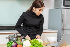 Woman is learning to cook by herself at home, online cooking course photo