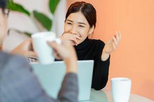 Mujer asiática sentada y charlando con colegas en la cafetería después del trabajo