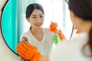 Hermosa mujer asiática limpiando el espejo en el baño.
