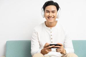 Hombre asiático usando audífonos inalámbricos y jugando juegos en su teléfono