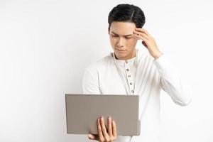 empresario asiático sosteniendo su cabeza mientras usa la computadora foto