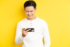 Hombre asiático sostiene su teléfono para ver una película sobre un fondo amarillo