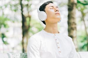 Handsome Asian man enjoying music at the park photo