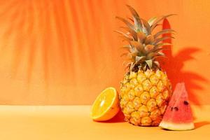 concepto de verano con naranja, piña y sandía y fondo naranja foto