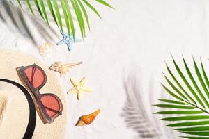 fondo de verano con concha, gafas de sol y sombrero en la arena