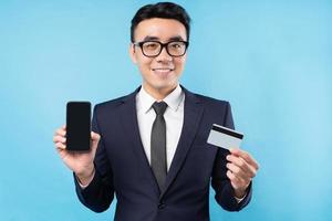 hombre de negocios asiático vistiendo traje sosteniendo teléfono inteligente y tarjeta bancaria