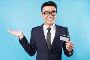 Asian businessman holding bank card on blue background photo