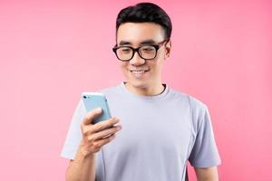 Retrato de hombre asiático con smartphone sobre fondo rosa