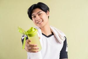 Hombre asiático sosteniendo agua en la mano sobre fondo verde foto