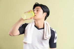 Hombre asiático está bebiendo agua sobre fondo verde foto
