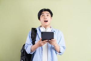 estudiante asiático masculino que estaba usando la tableta y miró hacia arriba con una expresión de sorpresa foto