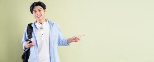 Male Asian student is smiling and pointing his finger to the left side photo