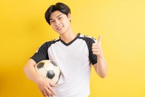 el hombre asiático sostiene la pelota y levanta el pulgar
