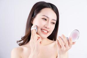 Joven asiática sentada sosteniendo una caja de maquillaje con una cara feliz foto