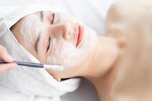 Mujer asiática haciendo tratamientos de belleza, tratamientos de spa y se le aplica crema en la cara foto