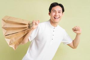 The handsome Asian man is holding paper bags in his hand photo