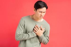 A photo of a handsome Asian man holding his arms around his chest because of a heart attack