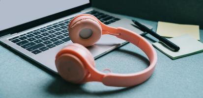 Image of laptop with white screen and pink headphones beside photo