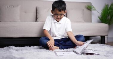 ragazzo asiatico con gli occhiali legge un libro e poi gioca. video