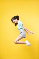 Young Asian girl jumping on yellow baclground photo