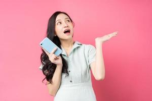 Joven mujer asiática sosteniendo el teléfono y mirando hacia arriba con entusiasmo