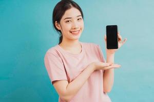 Portrait of girl holding phone and pointing at it on blue background photo