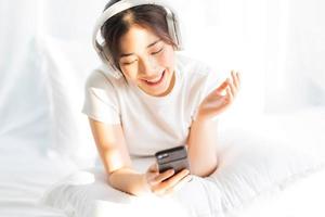 Young girl sitting in bed listening to entertaining music photo