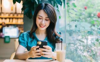 joven mujer asiática sonriendo mientras usa el teléfono inteligente