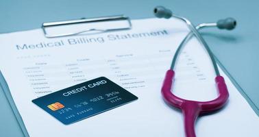 Top view picture of medical billing statement, cradit card,  and pink stethoscope on the gray background photo