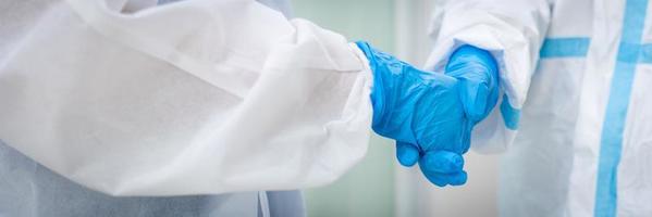 Banner picture of doctor in personal protective equipments or PPE shaking hands after meeting in the hospital. covid-19, coronavirus concept photo