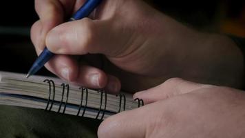 Close-up of a man writing notes on a notebook video